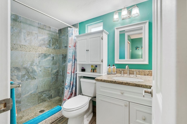 bathroom featuring a textured ceiling, toilet, walk in shower, and vanity