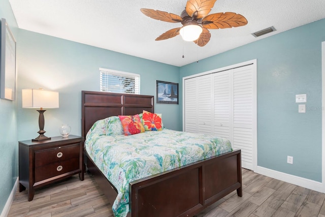 bedroom featuring ceiling fan, light hardwood / wood-style floors, a textured ceiling, and a closet