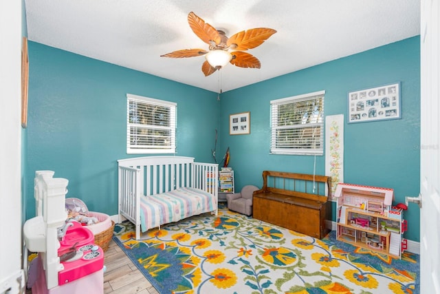 bedroom featuring ceiling fan, hardwood / wood-style flooring, and a crib