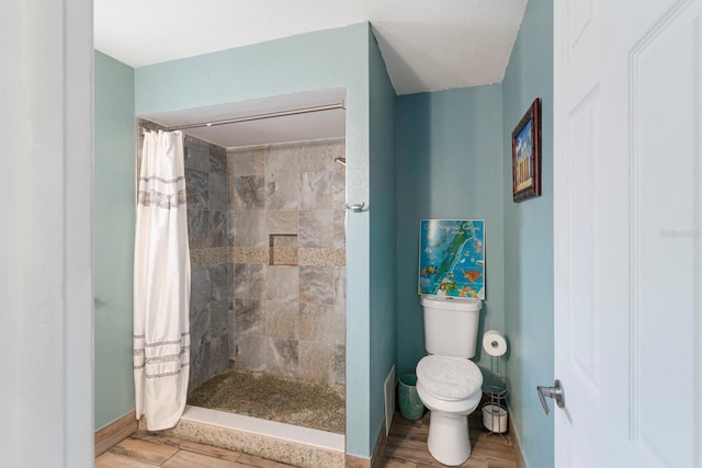 bathroom with toilet, a shower with shower curtain, and hardwood / wood-style flooring