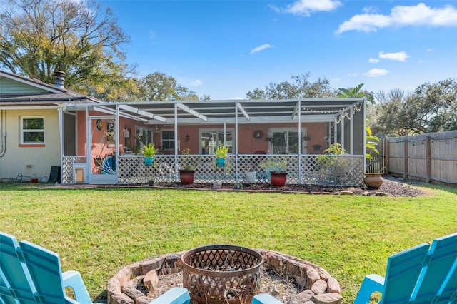 back of house featuring a lanai, a yard, and a fire pit