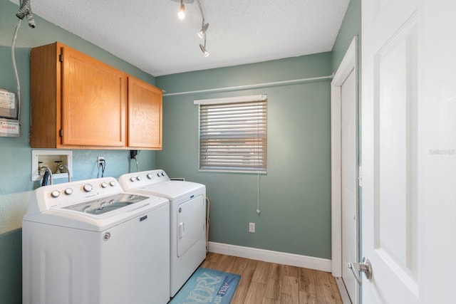 laundry area featuring washer and dryer, cabinets, a textured ceiling, and light wood-type flooring