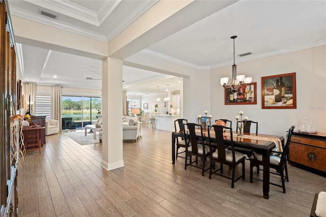 dining room with an inviting chandelier, ornamental molding, and light wood-type flooring