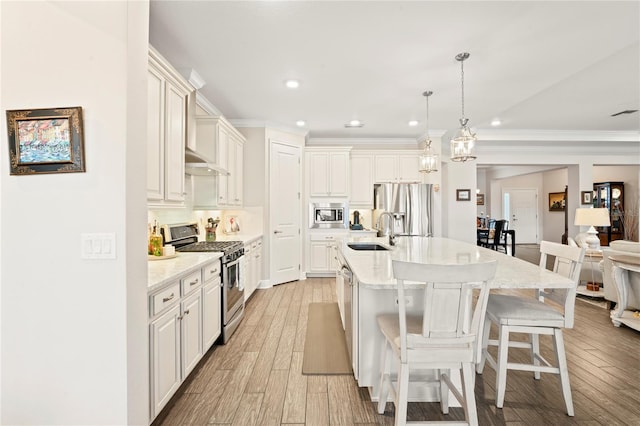 kitchen with appliances with stainless steel finishes, pendant lighting, sink, a kitchen breakfast bar, and a kitchen island with sink