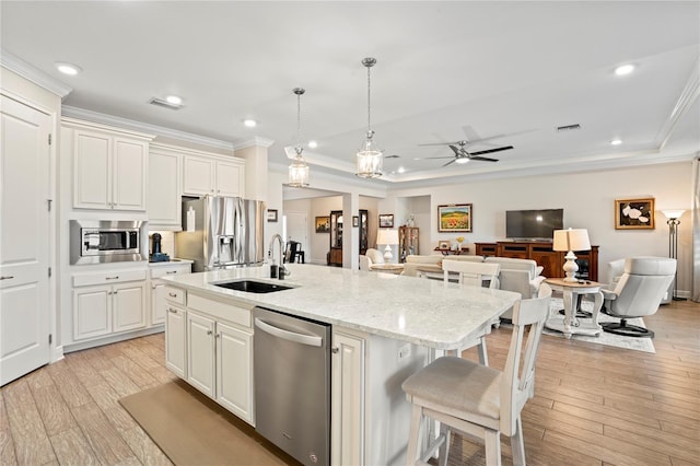 kitchen with a breakfast bar, sink, a center island with sink, stainless steel appliances, and white cabinets