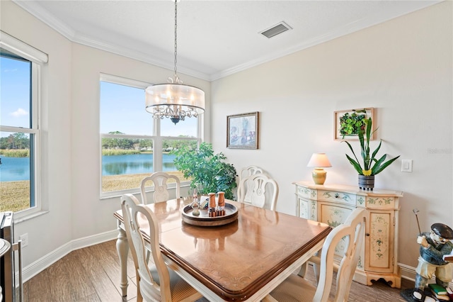 dining area with hardwood / wood-style flooring, ornamental molding, a water view, and a wealth of natural light