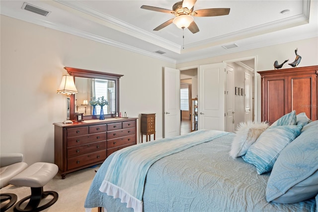 bedroom with crown molding, light carpet, ceiling fan, and a tray ceiling