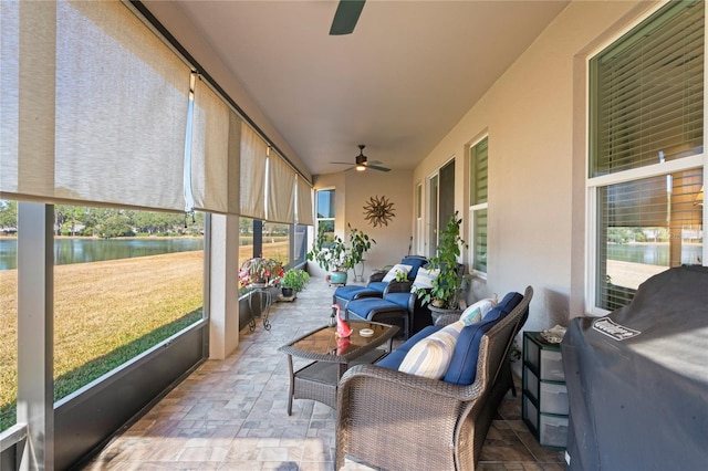 sunroom featuring a water view and ceiling fan