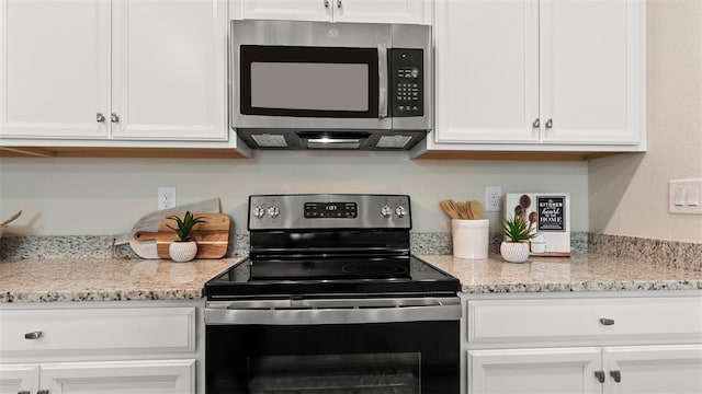 kitchen with stainless steel appliances, light stone countertops, and white cabinets