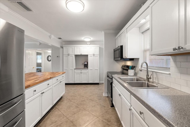 kitchen with white cabinets, appliances with stainless steel finishes, decorative backsplash, sink, and ornamental molding