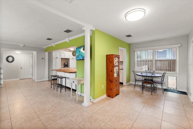 tiled dining area with ornate columns and crown molding