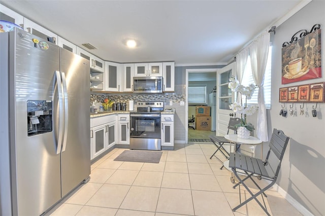 kitchen featuring stainless steel appliances, visible vents, backsplash, light tile patterned flooring, and white cabinetry