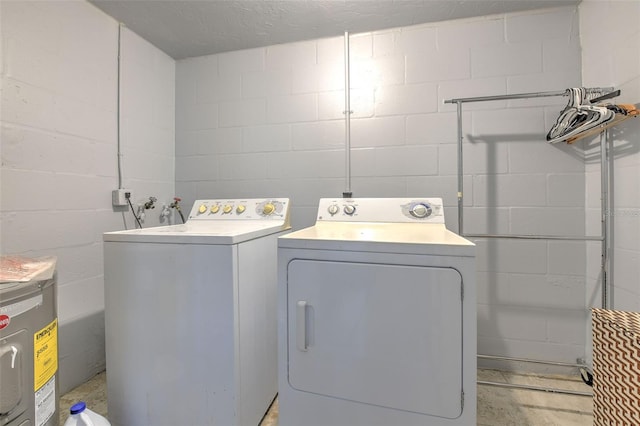 laundry area featuring electric water heater, laundry area, washing machine and dryer, and concrete block wall