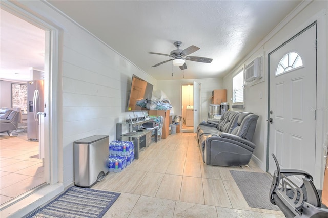 living room with a textured ceiling, an AC wall unit, light tile patterned floors, ornamental molding, and ceiling fan