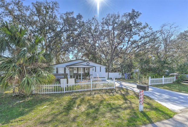 view of front of home featuring a fenced front yard, concrete driveway, and a front yard