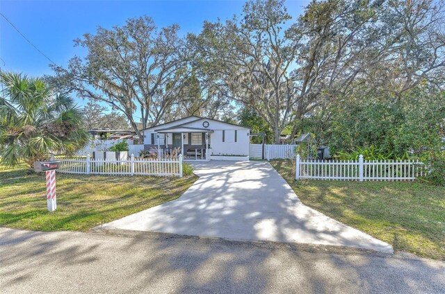 view of front of property with driveway, a fenced front yard, and a front lawn