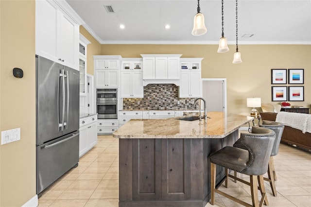 kitchen with sink, a center island with sink, pendant lighting, stainless steel appliances, and white cabinets