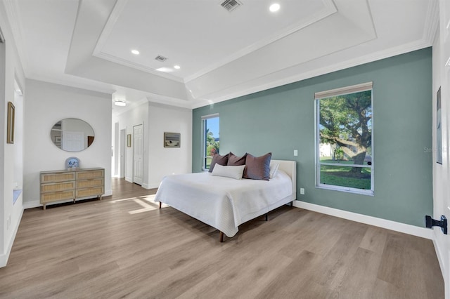 bedroom with a raised ceiling, ornamental molding, and light hardwood / wood-style flooring