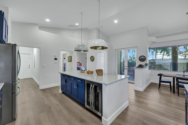 kitchen featuring light stone countertops, decorative light fixtures, blue cabinetry, stainless steel fridge, and high vaulted ceiling