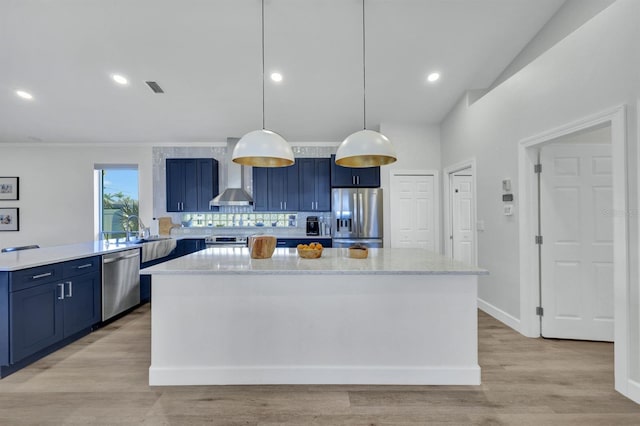 kitchen featuring kitchen peninsula, hanging light fixtures, appliances with stainless steel finishes, blue cabinetry, and wall chimney exhaust hood