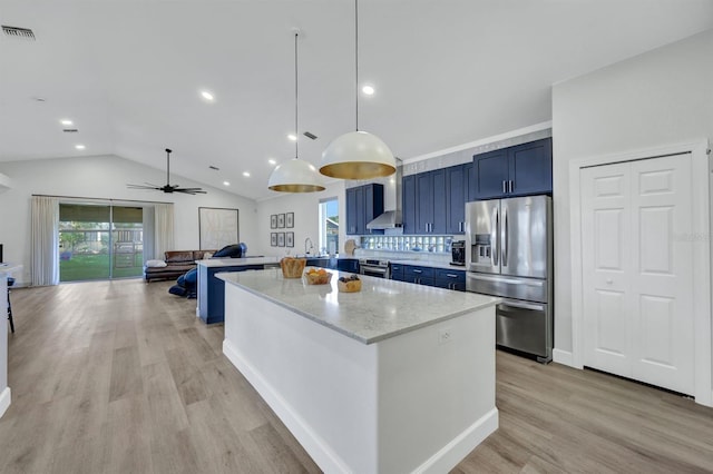 kitchen with appliances with stainless steel finishes, hanging light fixtures, wall chimney exhaust hood, light stone counters, and a center island