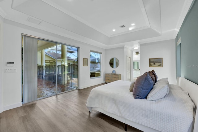 bedroom featuring hardwood / wood-style floors, access to exterior, ornamental molding, and a raised ceiling