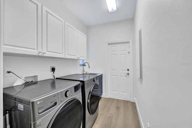 laundry area with cabinets, light hardwood / wood-style floors, washer and clothes dryer, and sink