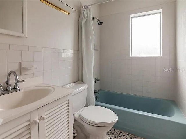 full bathroom with tile walls, toilet, vanity, and shower / tub combo