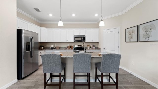 kitchen featuring light stone countertops, stainless steel appliances, white cabinets, and a center island with sink