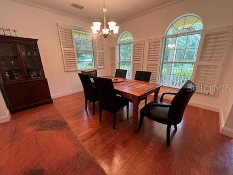 dining area featuring dark wood-type flooring, an inviting chandelier, and ornamental molding