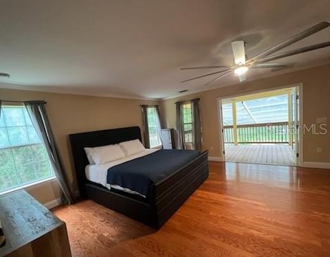 bedroom with ceiling fan, access to exterior, multiple windows, and hardwood / wood-style floors