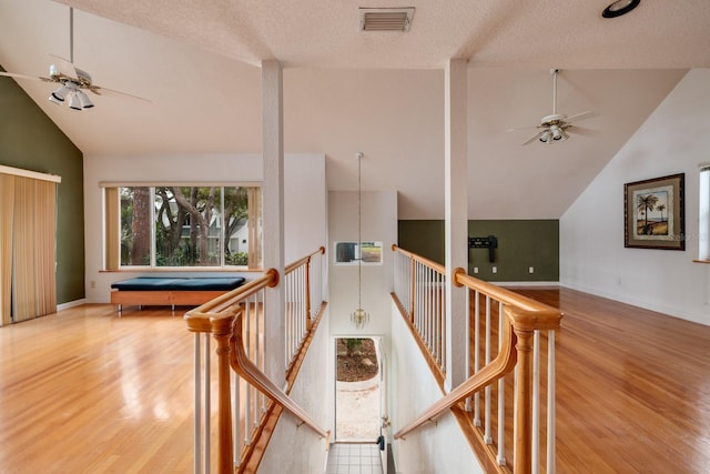 hall with a textured ceiling, wood-type flooring, and high vaulted ceiling