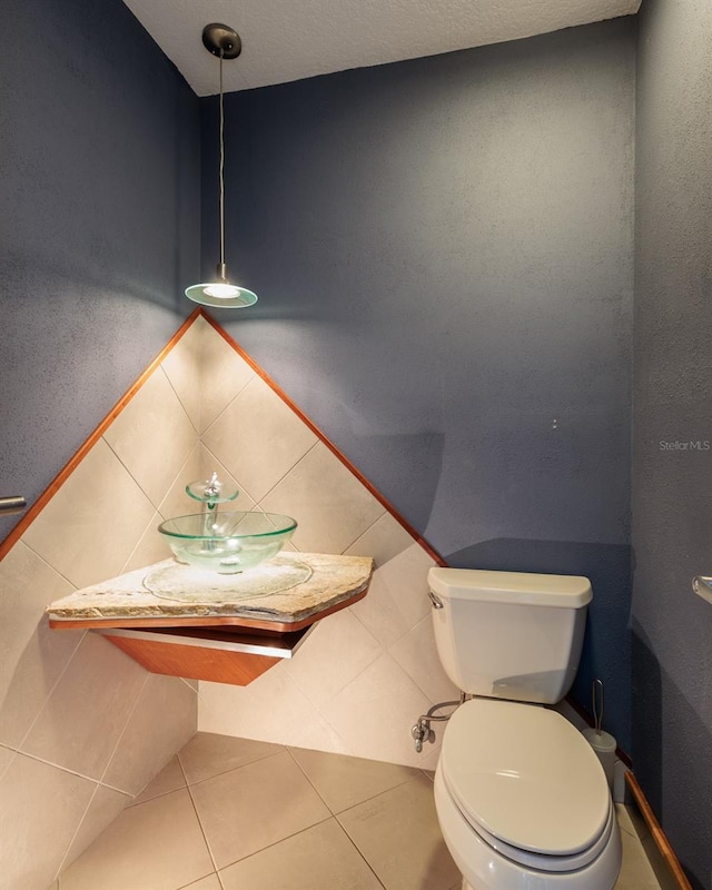 bathroom featuring toilet, tile patterned flooring, tile walls, and backsplash