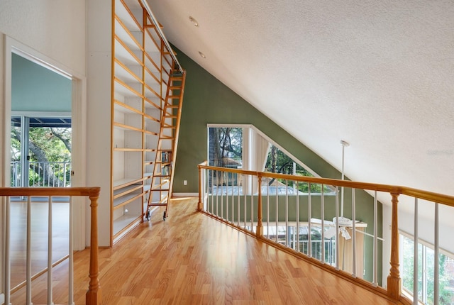 interior space with high vaulted ceiling, a textured ceiling, and hardwood / wood-style flooring