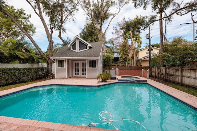 view of swimming pool with an outbuilding, french doors, and an in ground hot tub