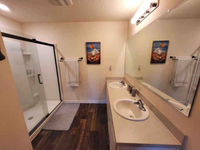 bathroom with a shower with shower door, vanity, a textured ceiling, and hardwood / wood-style floors