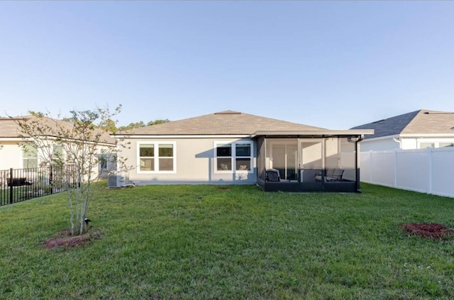 rear view of house featuring central AC unit, a sunroom, and a yard