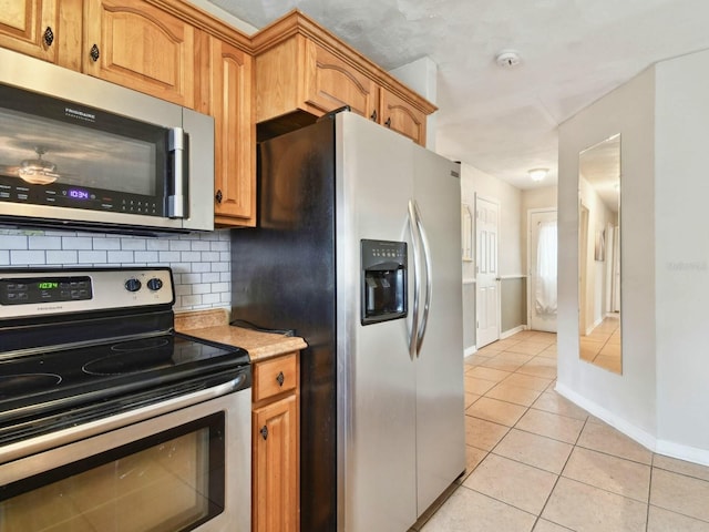 kitchen featuring light tile patterned floors, stainless steel appliances, and tasteful backsplash