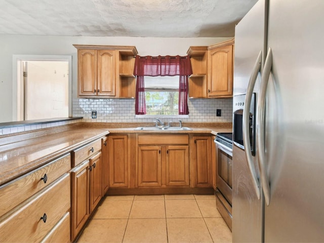 kitchen with a textured ceiling, appliances with stainless steel finishes, tasteful backsplash, sink, and light tile patterned flooring