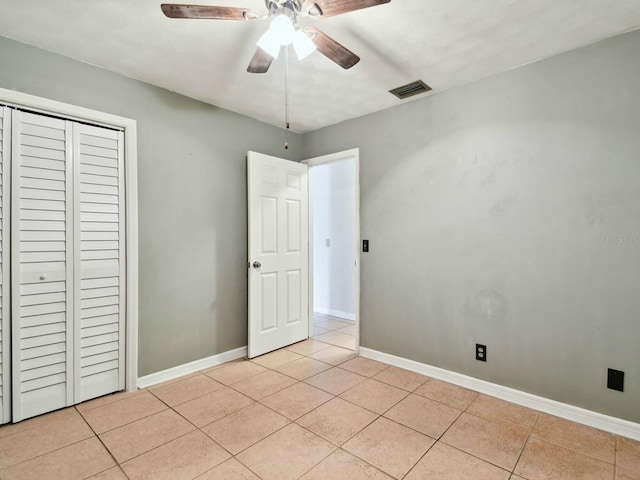 unfurnished bedroom with ceiling fan, light tile patterned floors, and a closet