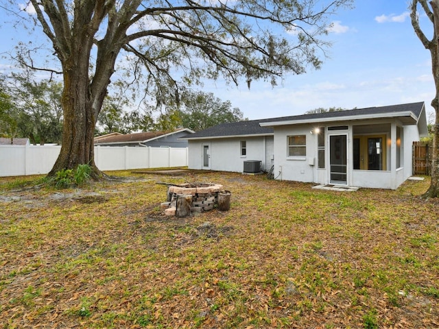 back of house featuring a lawn, an outdoor fire pit, cooling unit, and a sunroom