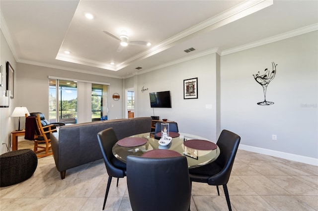 tiled dining space with ceiling fan, ornamental molding, and a raised ceiling