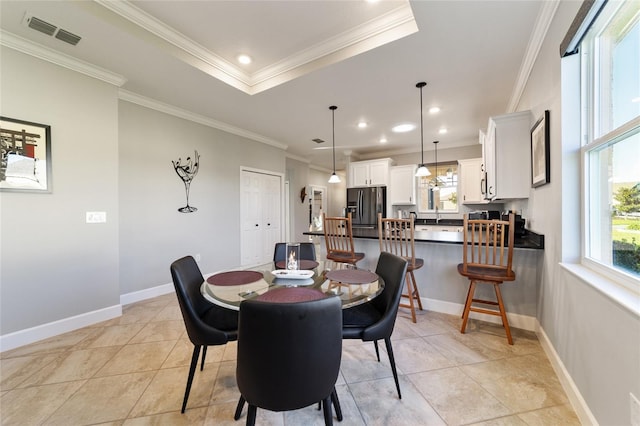 tiled dining room with a raised ceiling and crown molding