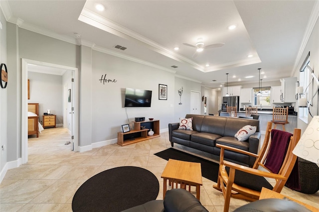 tiled living room featuring ceiling fan, a tray ceiling, and crown molding