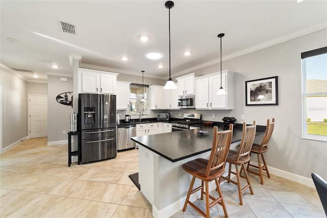 kitchen with hanging light fixtures, sink, white cabinetry, a breakfast bar area, and stainless steel appliances