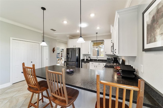 kitchen featuring sink, white cabinets, pendant lighting, and stainless steel appliances