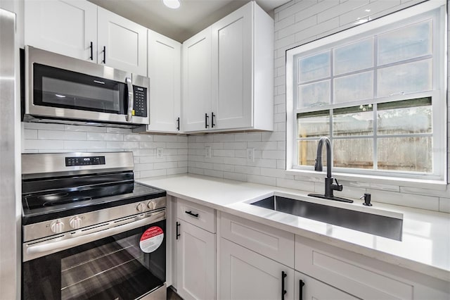 kitchen featuring stainless steel appliances, tasteful backsplash, sink, and white cabinets