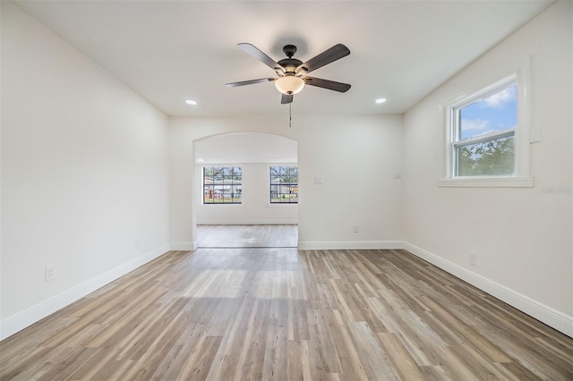 empty room with a wealth of natural light, light hardwood / wood-style flooring, and ceiling fan