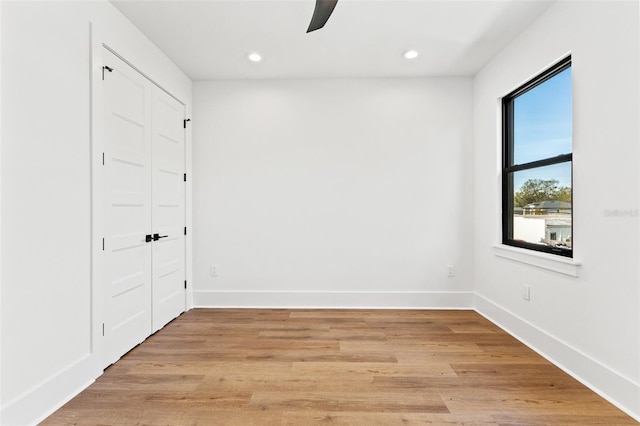 empty room with ceiling fan and light hardwood / wood-style flooring