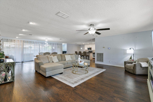 living room with ceiling fan, dark hardwood / wood-style flooring, and a textured ceiling